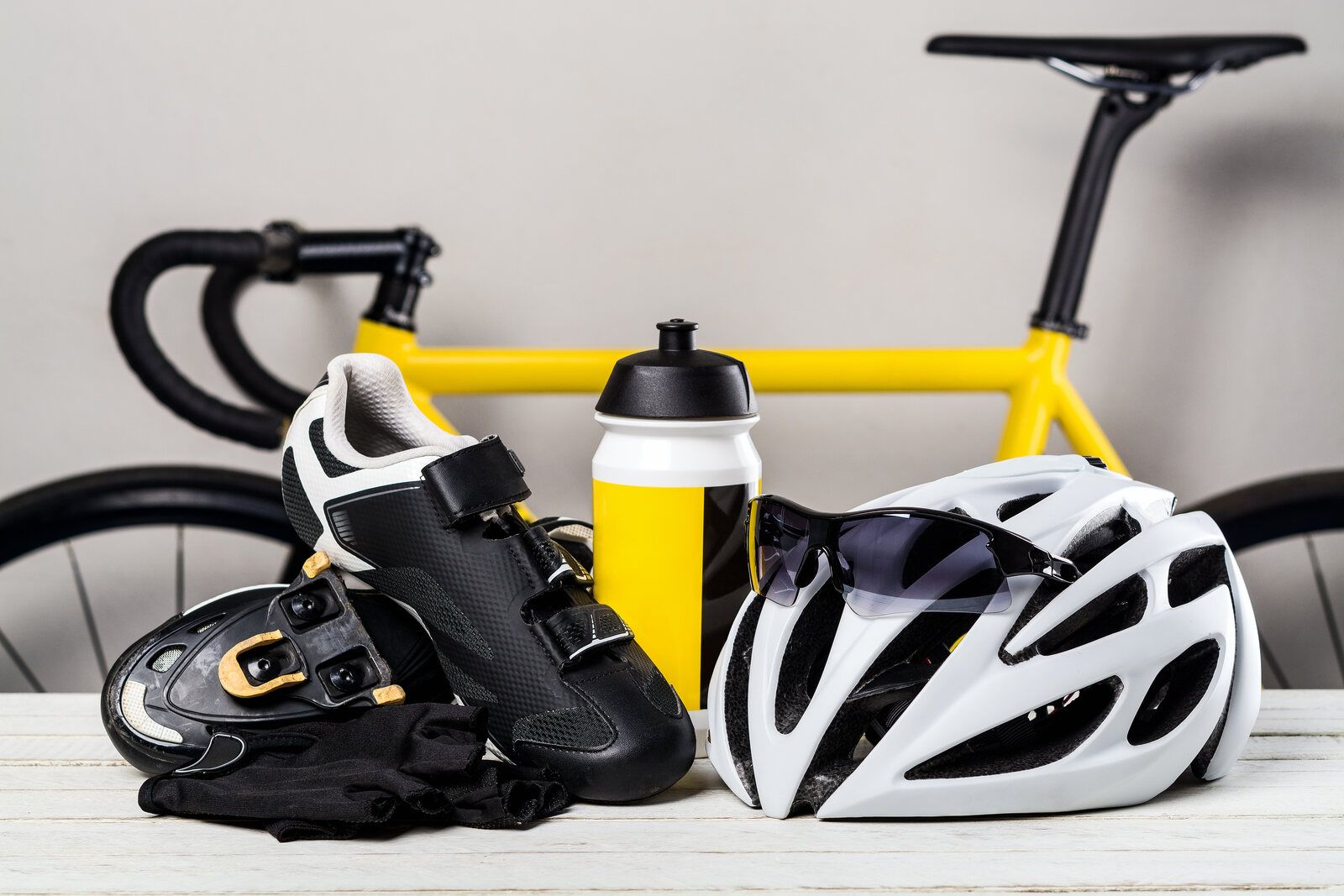 Verschiedenes Fahrradzubehör wie Helm, Sonnenbrille und Flasche liegen vor einem Fahrrad